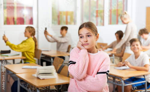 фотографія Portrait of unhappy kid girl studying in classroom at secondary school, learning