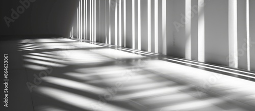 Abstract background of gray shadows and light blending on a white wall through a window. Architectural stripes casting dark shadows indoors, creating a monochrome black and white room ambiance.