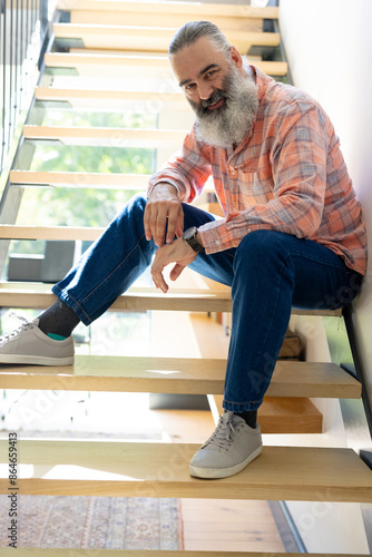 At home, Smiling senior man sitting on stairs, wearing casual clothes, looking relaxed © WavebreakMediaMicro
