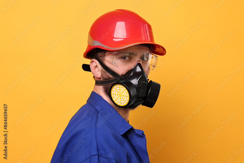 Man in respirator mask and hard hat on yellow background Man in respirator mask and hard hat on yellow background
