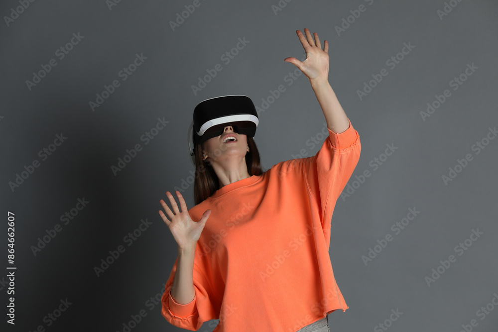 Surprised woman using virtual reality headset on gray background Surprised woman using virtual reality headset on gray background