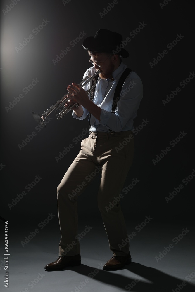 Fototapeta premium Professional musician playing trumpet on dark background