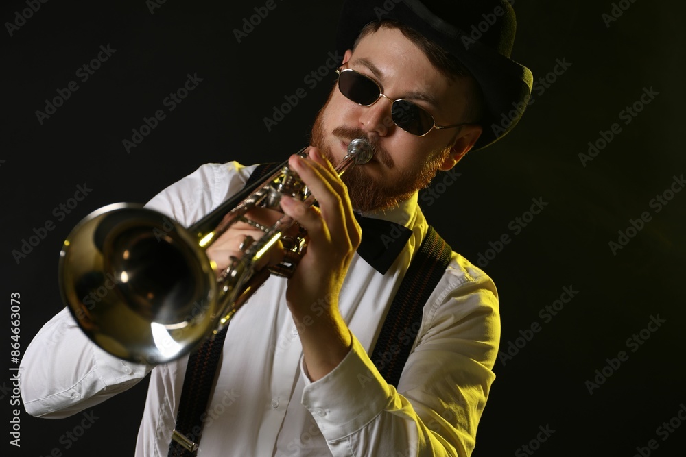 Obraz premium Professional musician playing trumpet on black background in color lights