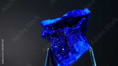 Azurite deep blue mineral from Morocco (Cu3(CO3)2(OH)2). Hardness scale: 3.5-4.5. Often used in jewelry and as art pigment. Close-up crystal formations and vibrant hues. Smooth rotation in Metal tweez