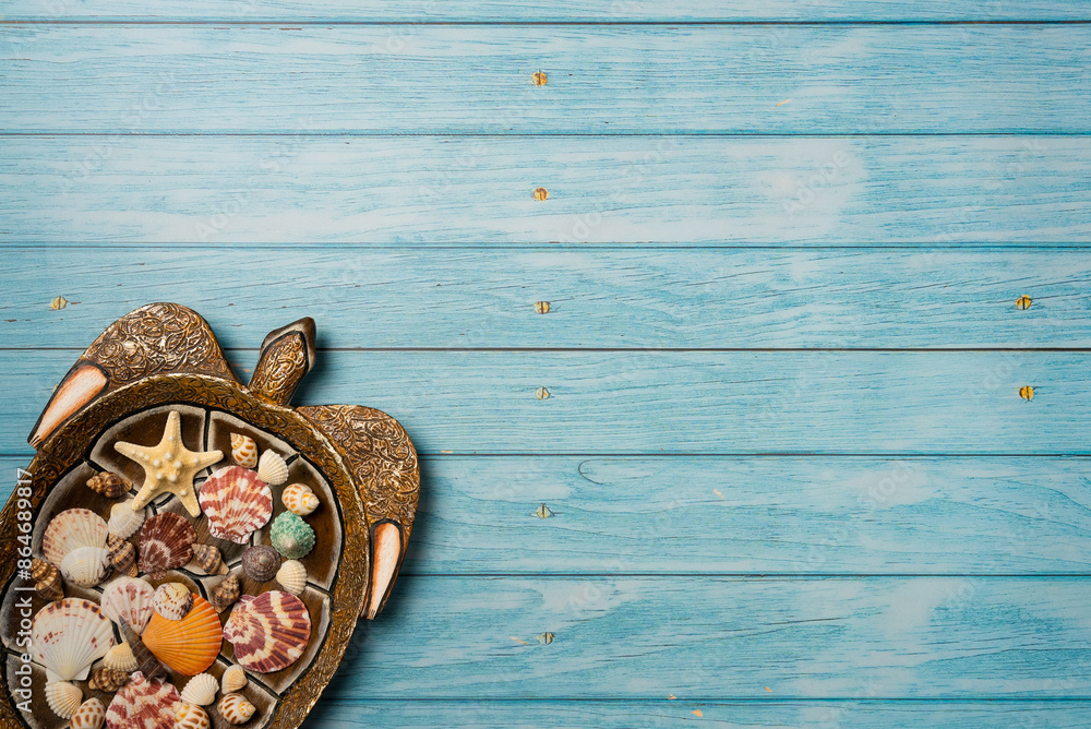 Starfish and many seashells on a decorative plate in the shape of a turtle. Blue wooden background. Top view, copy space Starfish and many seashells on a decorative plate in the shape of a turtle. Blue wooden background. Top view, copy space