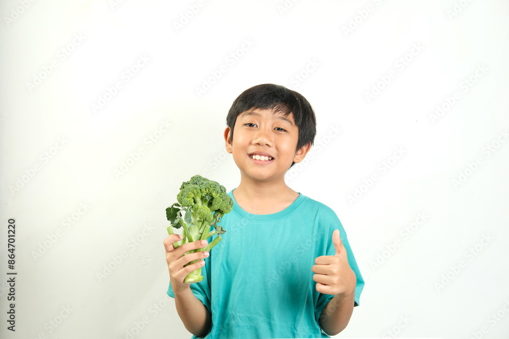 A cheerful child smiles while holding fresh broccoli and giving a thumbs up, promoting healthy eating. Ideal for health campaigns, nutritional content, and child wellness promotions. A cheerful child smiles while holding fresh broccoli and giving a thumbs up, promoting healthy eating. Ideal for health campaigns, nutritional content, and child wellness promotions.