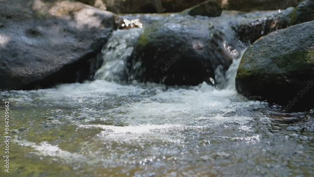 A small waterfall flows over black rocks. A small waterfall flows over black rocks.