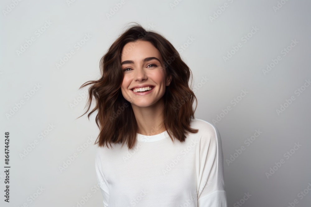 Portrait of beautiful young woman looking at camera and smiling while standing against grey background Portrait of beautiful young woman looking at camera and smiling while standing against grey background