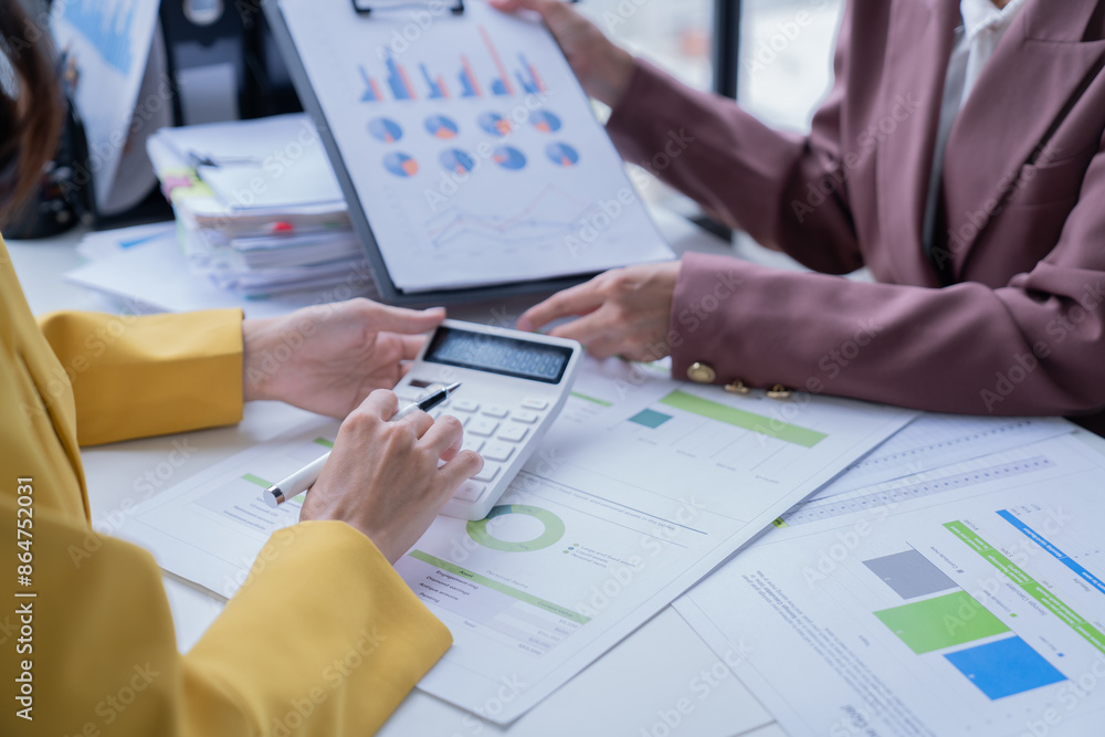 A professional photograph depicting two female entrepreneurs engaged in a collaborative discussion while diligently working in their corporate office environment. A professional photograph depicting two female entrepreneurs engaged in a collaborative discussion while diligently working in their corporate office environment.