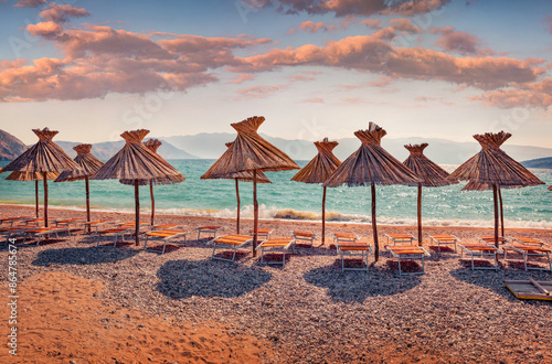 Fototapeta Naklejka Na Ścianę i Meble -  Warm evening scene of Baska Beach with straw umbrellas. Amazing summer seascape of Adriatic sea, Baska town location, Krk island, Kvarner bay archipelago, Croatia, Europe. Vacation concept background.
