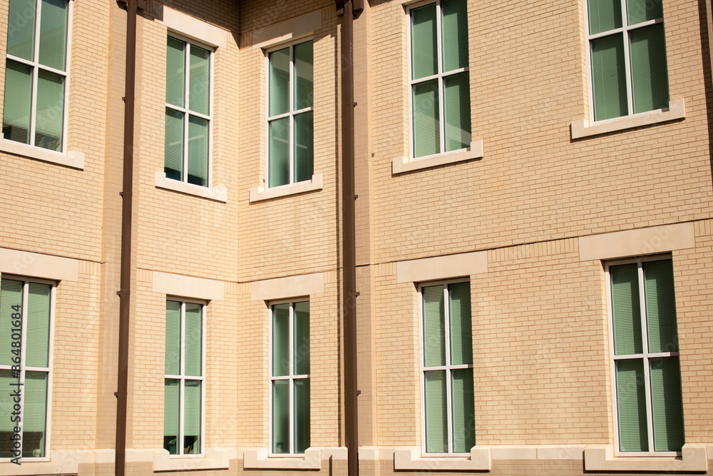 Multi-story building with sun shining directly on wall. Beige stucco exterior wall Multi-story building with sun shining directly on wall. Beige stucco exterior wall