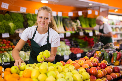 Obraz na plátně Fifteen-year-old girl who works part-time in a store as a trainee saleswoman put