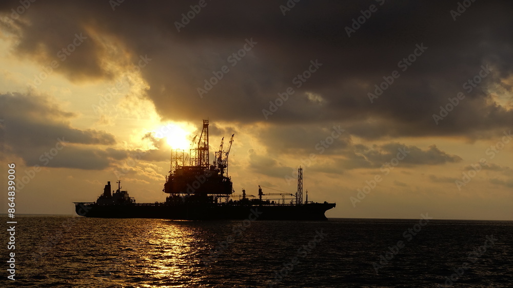 Drilling rig and FPSO ship or floating processing storage offloading ship silhouette view in sunset offshore background Drilling rig and FPSO ship or floating processing storage offloading ship silhouette view in sunset offshore background