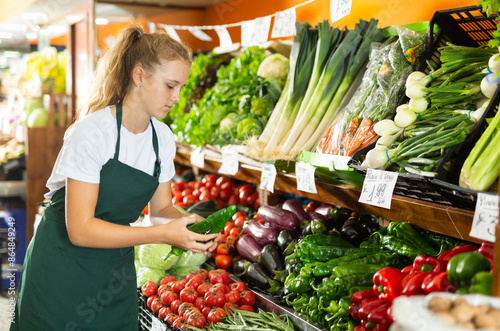 Obraz na plátně Focused fifteen-year-old girl who works part-time in a store as a trainee salesw