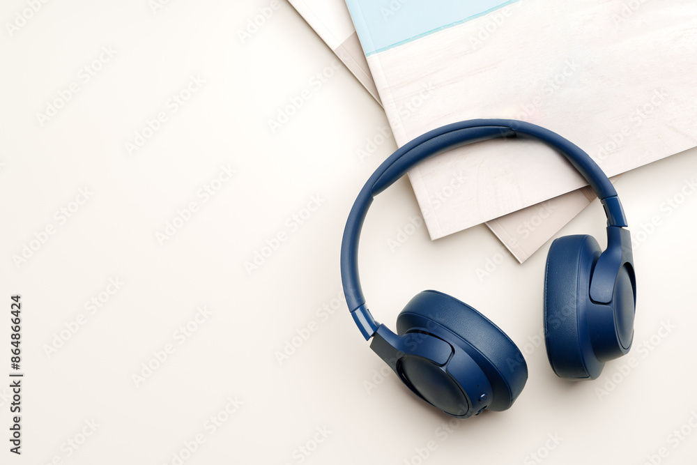 Blue headphones and stack of paper on white background Blue headphones and stack of paper on white background