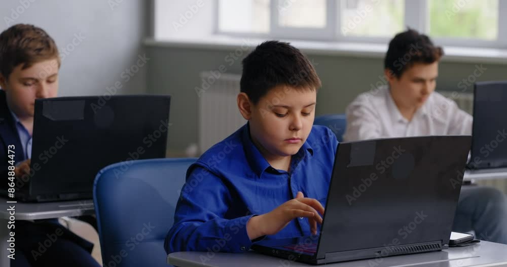 Caucasian Schoolboy Working With Laptop In Computer-Based Classroom, Coding And Programming Classes Caucasian Schoolboy Working With Laptop In Computer-Based Classroom, Coding And Programming Classes