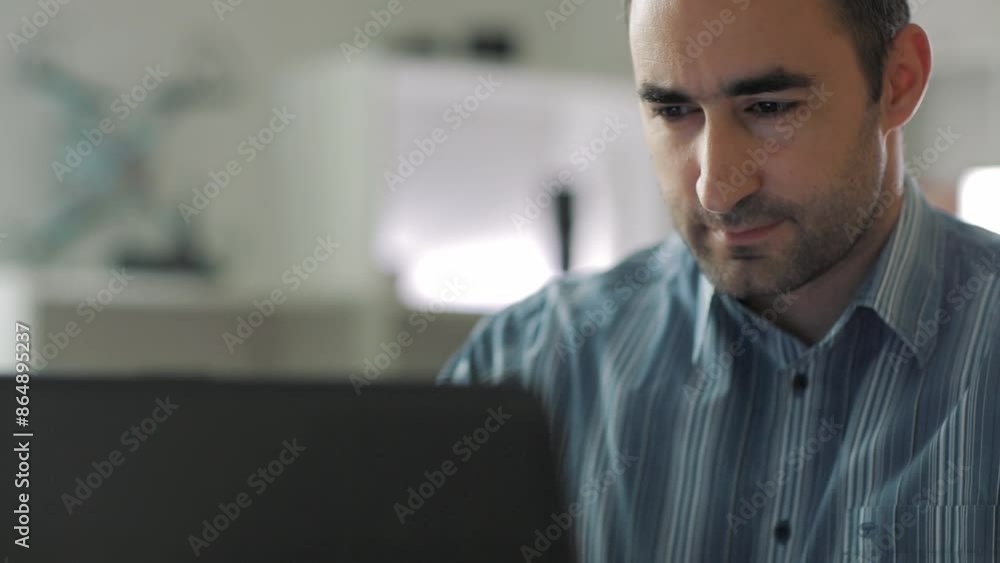 Middle aged man taping on the keyboard of the laptop computer while working at home
