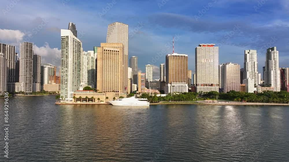 Skyline of Miami Downtown during golden sunrise. Reflecting Skyscraper Buildings in the morning. Docking Yacht on Pier. Aerial lateral wide shot. Skyline of Miami Downtown during golden sunrise. Reflecting Skyscraper Buildings in the morning. Docking Yacht on Pier. Aerial lateral wide shot.