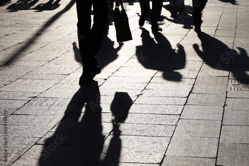 Black silhouettes and shadows of people on the street. Crowd walking down on sidewalk, concept of pedestrians, crime, society, city life