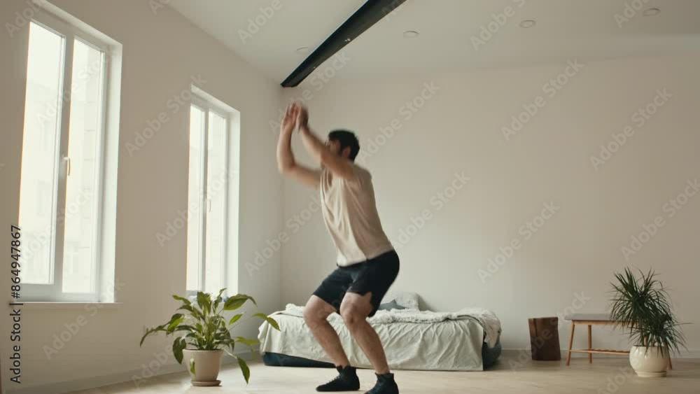Jump squats. Bearded man squatting and jumping, exercising at home Jump squats. Bearded man squatting and jumping, exercising at home