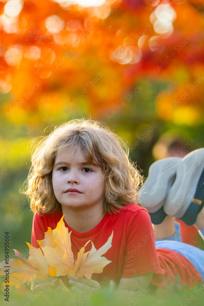 Cute blonde child rest on autumn park. Child play with autumn fall leaves. Kid laying down on the fall leaves in park outdoor. Fall autumn foliage concept. Kid boy playing with fall leaves in park. Cute blonde child rest on autumn park. Child play with autumn fall leaves. Kid laying down on the fall leaves in park outdoor. Fall autumn foliage concept. Kid boy playing with fall leaves in park.