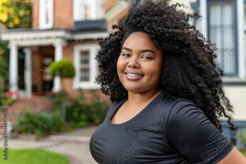 Confident young woman smiling in front of suburban house