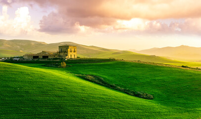 Fototapete Grün countryside sunset in green hills of spring fields with old castle farm and mountains on background of evening landscape  © Yaroslav