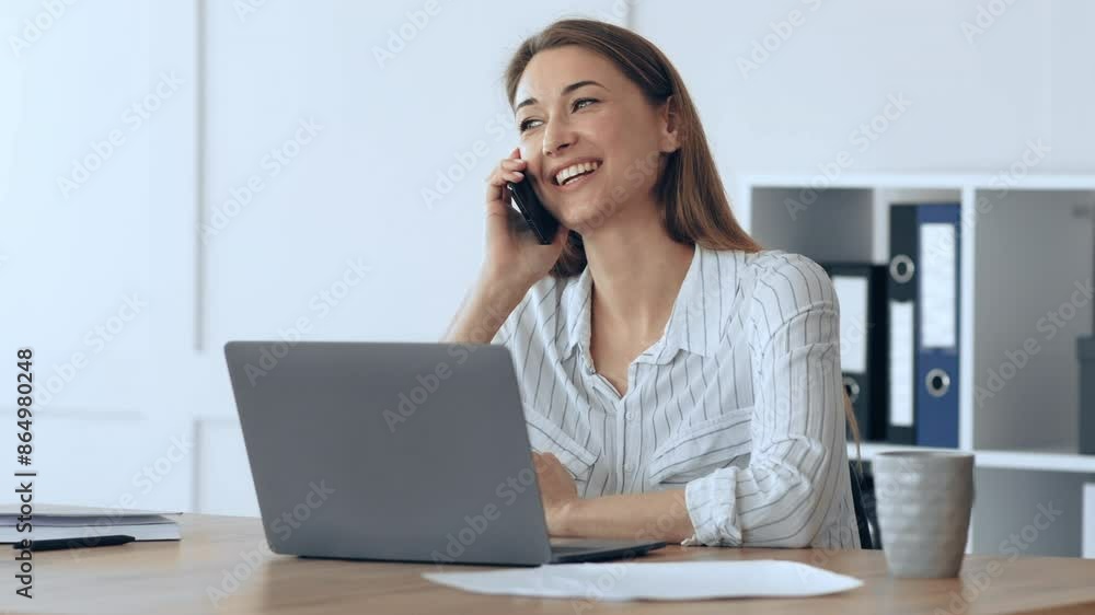 Friendly business woman talking on phone, working on laptop at home office Friendly business woman talking on phone, working on laptop at home office