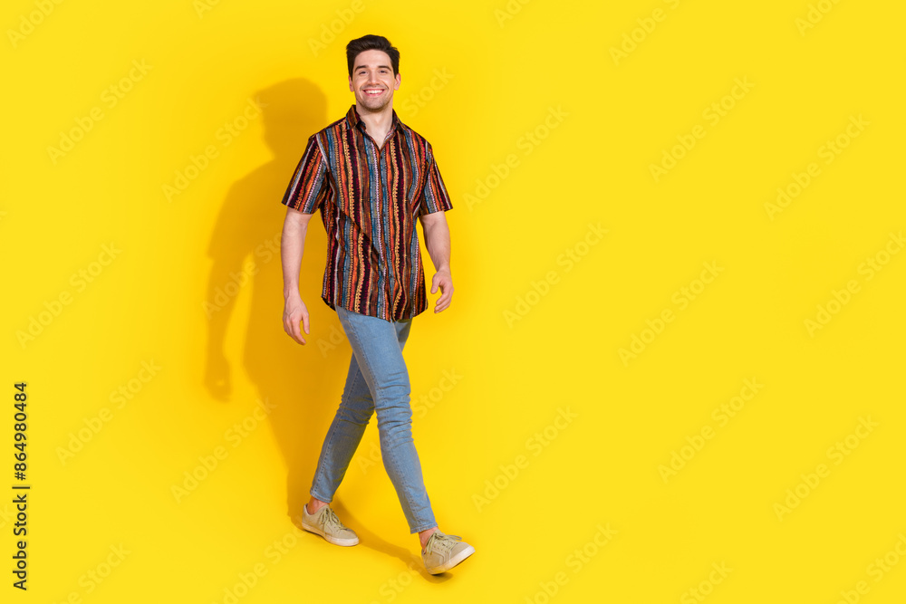 Full length portrait of nice young man walk empty space wear shirt isolated on yellow color background Full length portrait of nice young man walk empty space wear shirt isolated on yellow color background