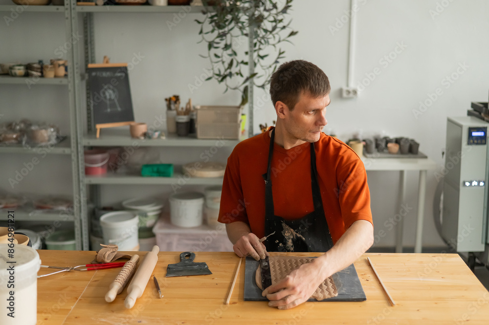 A potter cuts a piece of rolled clay with patterns. A potter cuts a piece of rolled clay with patterns.