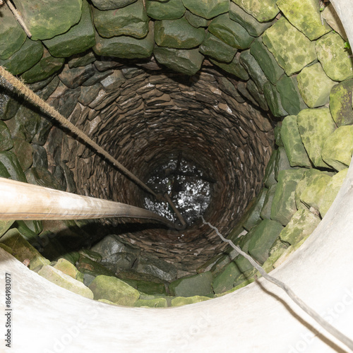 The village well is paved with stone, a view of the well in the middle. photo