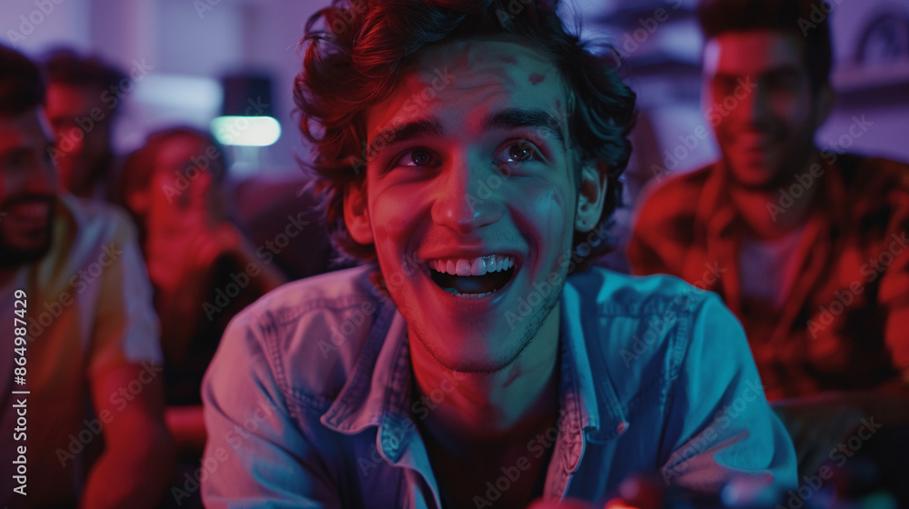 A young man in his early twenties experiencing a moment of amusement while playing a video game with friends, all showing joyful expressions A young man in his early twenties experiencing a moment of amusement while playing a video game with friends, all showing joyful expressions
