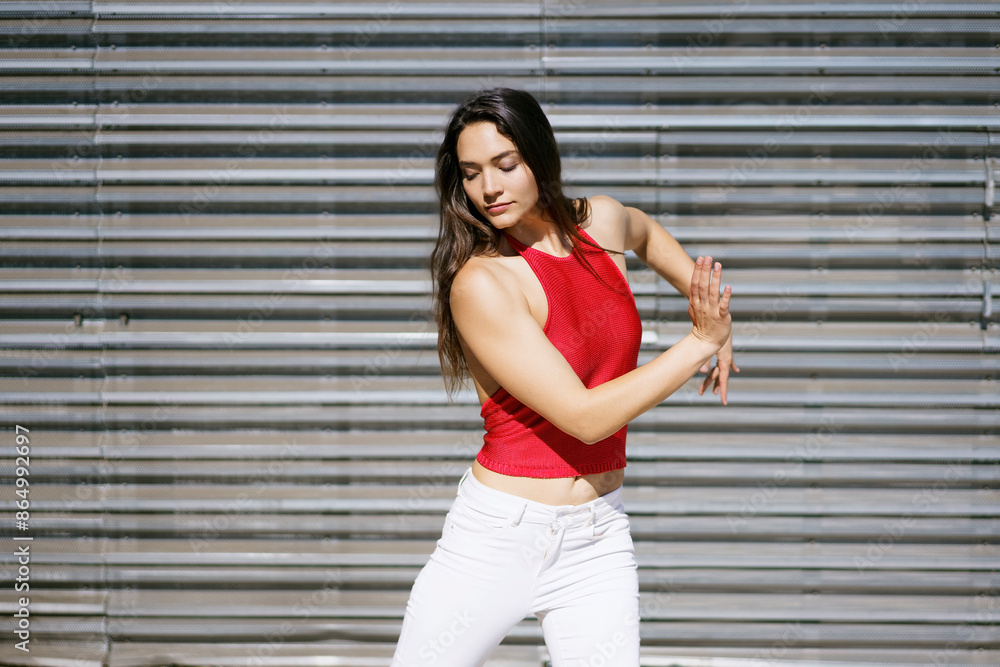Young woman dancing in front of wall on sunny day Young woman dancing in front of wall on sunny day