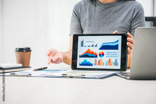 Fotografi A businesswoman works diligently at her desk, reviewing financial documents and analyzing investment data
