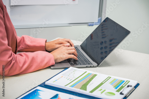 Fotografie A businesswoman works diligently at her desk, reviewing financial documents and analyzing investment data