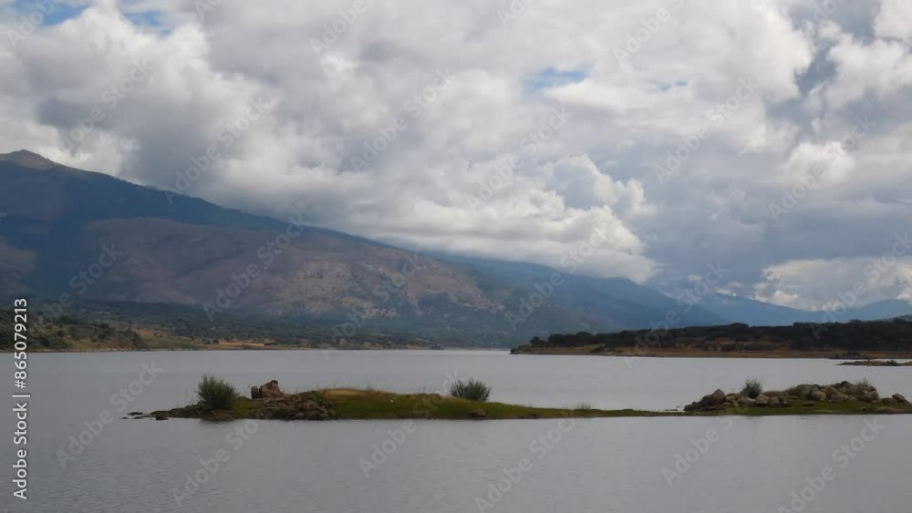 Serene landscape of a small island in the middle of a swamp with mountain range in the background and storm clouds in the sky Serene landscape of a small island in the middle of a swamp with mountain range in the background and storm clouds in the sky