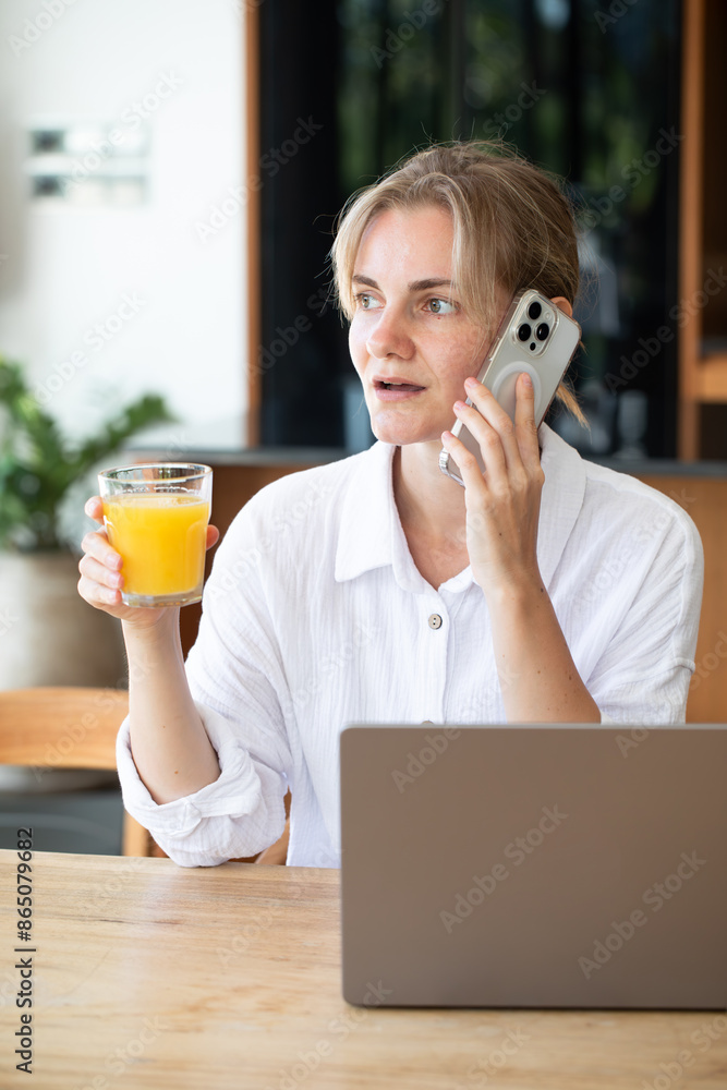 A woman works at a computer and talking on smartphone. Home office. Information Technology. Search for information on the Internet. Freelancing. A woman works at a computer and talking on smartphone. Home office. Information Technology. Search for information on the Internet. Freelancing.