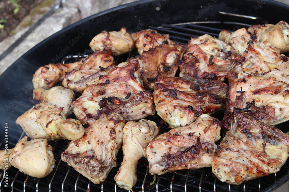 Chicken drumsticks are cooked over a fire on a barbecue grill. Chicken drumsticks are cooked over a fire on a barbecue grill.