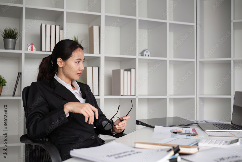 Young Female Accountant Sitting at Desk and Doing Paperwork in Modern Office Setting Young Female Accountant Sitting at Desk and Doing Paperwork in Modern Office Setting