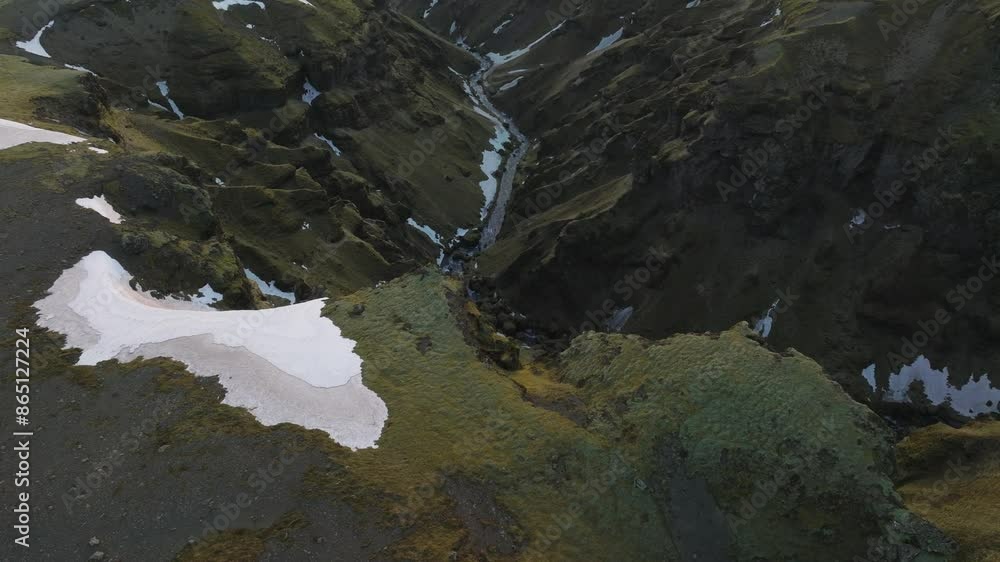 Aerial view of a mountain canyon with a river flowing from melting snow, in Iceland Aerial view of a mountain canyon with a river flowing from melting snow, in Iceland
