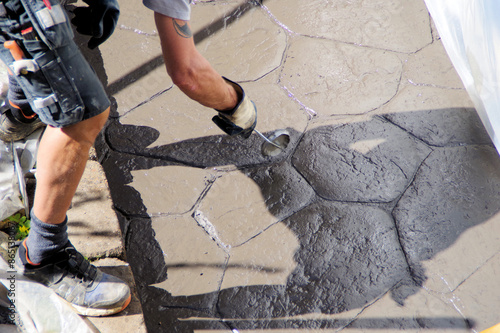 Man making pattern in concrete with tool on terazze.  photo