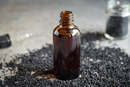 Black cumin or Nigella sativa seed oil in a dark brown glass bottle. Healthy anti-inflammatory and antioxidant supplement. photo