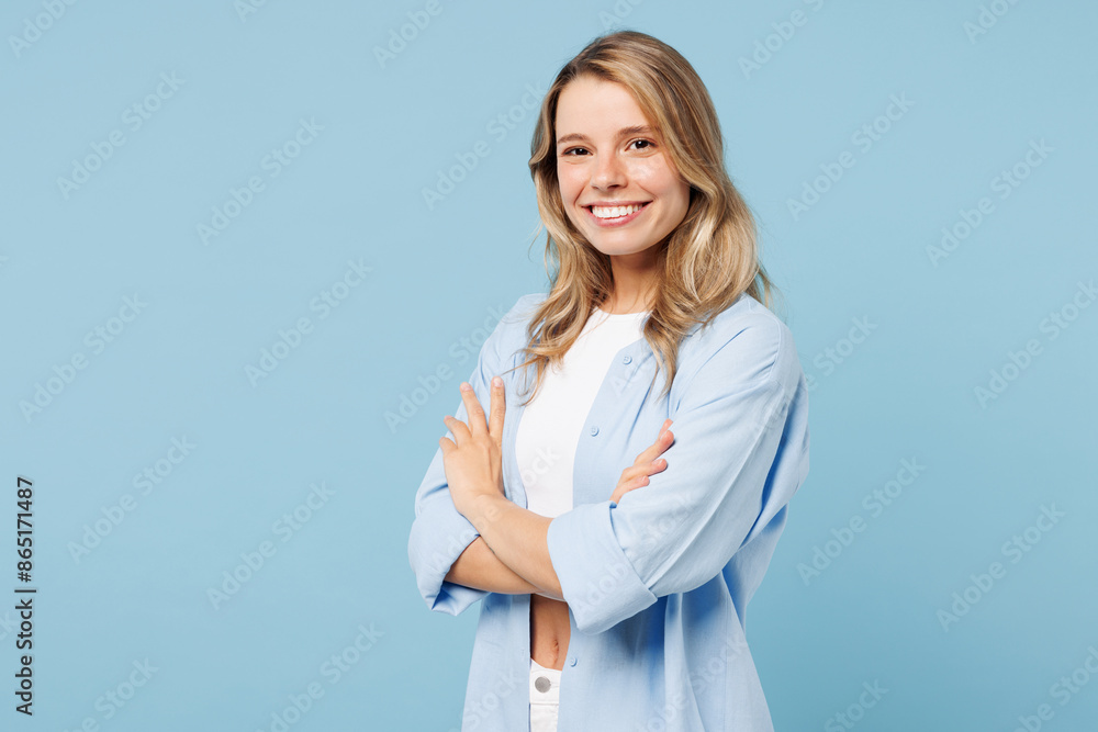 Side view young smiling happy woman wears white top shirt casual clothes hold hands crossed folded look camera isolated on plain pastel light blue cyan background studio portrait. Lifestyle concept. Side view young smiling happy woman wears white top shirt casual clothes hold hands crossed folded look camera isolated on plain pastel light blue cyan background studio portrait. Lifestyle concept.
