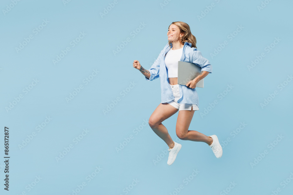 Full body young happy IT woman wears white top shirt casual clothes jump high run fast hold laptop pc computer isolated on plain pastel light blue cyan background studio portrait. Lifestyle concept. Full body young happy IT woman wears white top shirt casual clothes jump high run fast hold laptop pc computer isolated on plain pastel light blue cyan background studio portrait. Lifestyle concept.