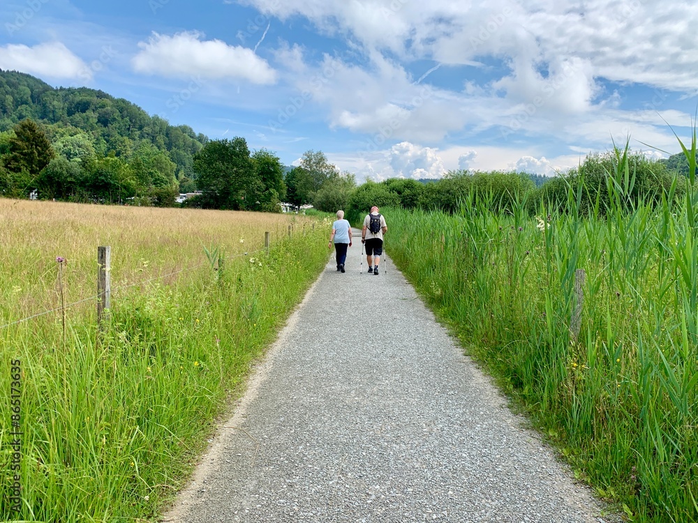 Obraz premium Fussweg / Wanderweg mit zwei Wanderer, Frau und Mann , Liebespaar, auf Wanderung durch die Wiese, Natur.