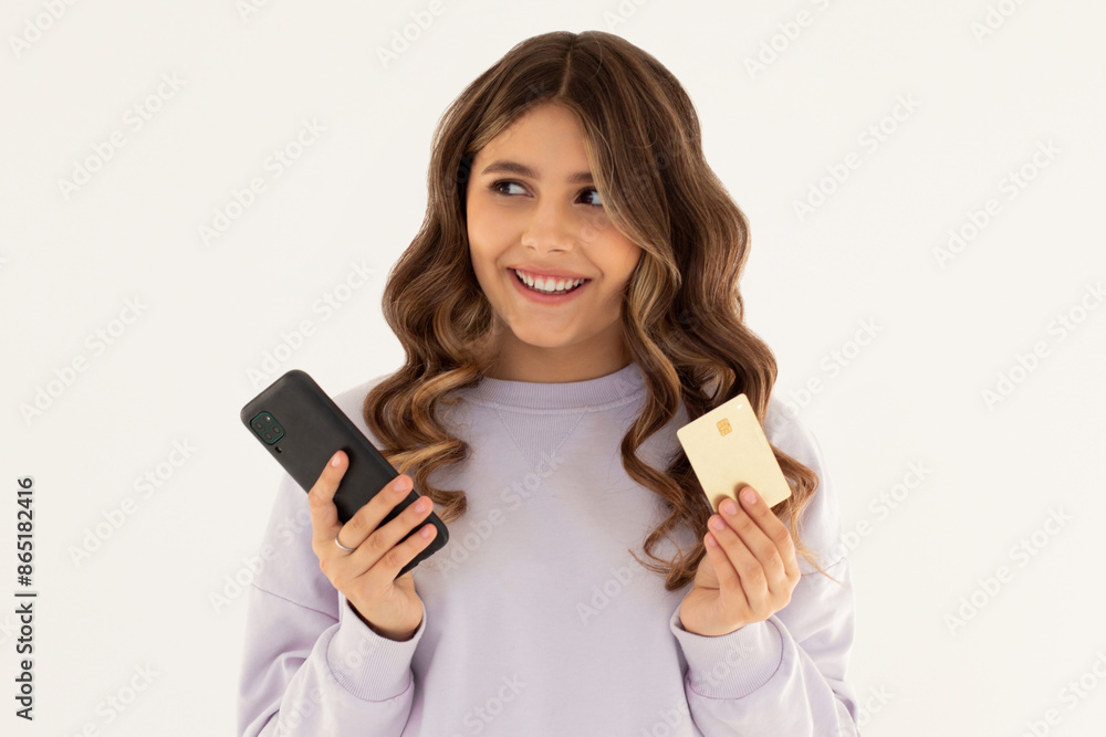 Online shopping. Smiling good-looking woman paying for order, using plastic credit card to pay with mobile phone, standing against white background Online shopping. Smiling good-looking woman paying for order, using plastic credit card to pay with mobile phone, standing against white background
