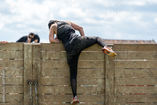A female athlete climbing over a wall in an obstacle course race