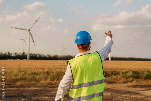 Maintenance engineer checking wind turbine farm on a field. Portrait of skilled professional. European green deal photo