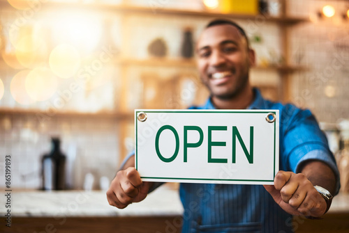 Coffee shop, smile and man with open sign for small business, startup and retail store. Restaurant, cafeteria employee and happy waiter, barista and owner by counter for service, help and welcome