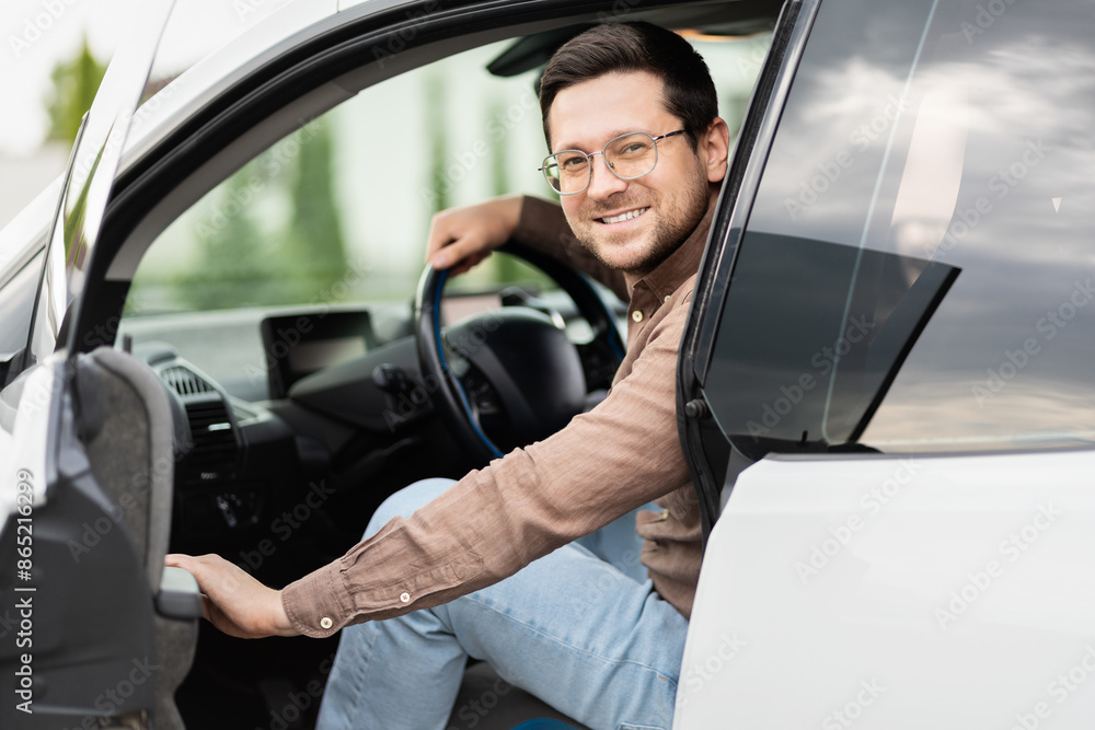 Young Man With Glasses Sitting In Car, Smiling At Camera, Concept Of Transportation, Comfort, And Lifestyle, Modern Vehicle Young Man With Glasses Sitting In Car, Smiling At Camera, Concept Of Transportation, Comfort, And Lifestyle, Modern Vehicle